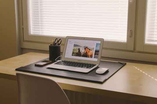 A desk with a laptop and notebook